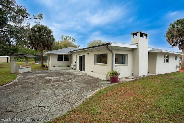 back of property with a lawn and a patio