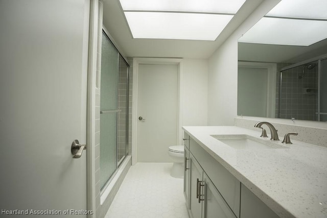 bathroom with toilet, a skylight, an enclosed shower, and vanity