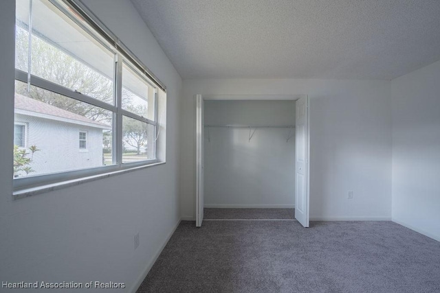 unfurnished bedroom featuring dark carpet, a closet, and a textured ceiling