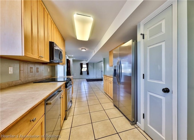 kitchen with light tile patterned flooring, appliances with stainless steel finishes, backsplash, and light brown cabinets