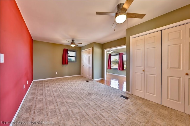 interior space with light carpet, two closets, and ceiling fan