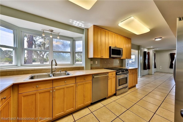 kitchen with tasteful backsplash, sink, light tile patterned floors, and appliances with stainless steel finishes