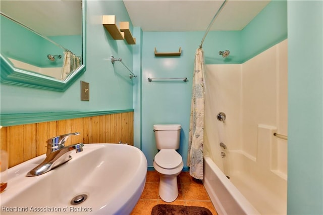 full bathroom with sink, tile patterned flooring, shower / bath combination with curtain, toilet, and wood walls