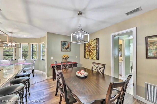 dining area with light hardwood / wood-style floors and an inviting chandelier