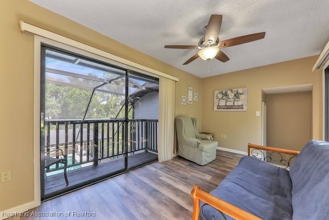 living room with hardwood / wood-style floors, ceiling fan, and a textured ceiling