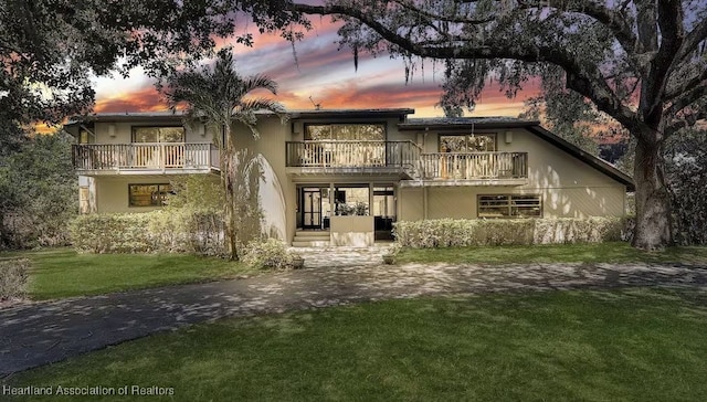 view of front of home with a yard and a balcony