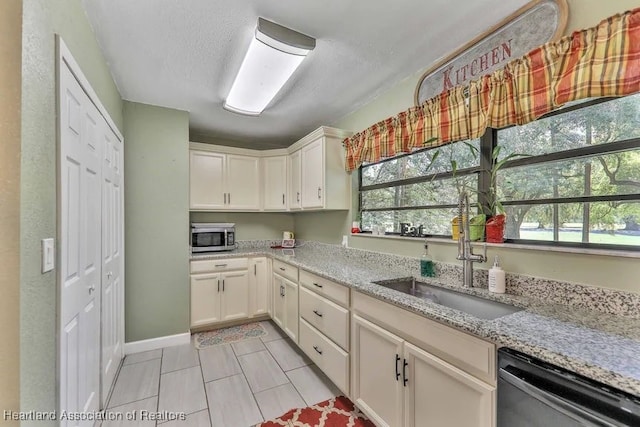 kitchen featuring a wealth of natural light, light stone countertops, sink, light tile patterned flooring, and appliances with stainless steel finishes