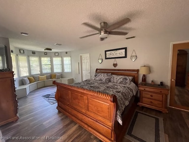 bedroom with ceiling fan, dark hardwood / wood-style flooring, and a textured ceiling