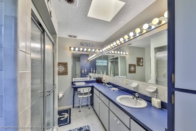 bathroom with decorative backsplash, tile patterned flooring, vanity, and a textured ceiling