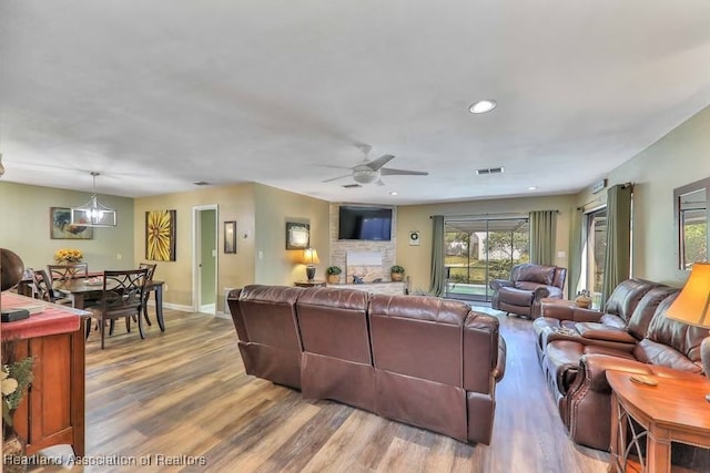 living room with ceiling fan with notable chandelier and hardwood / wood-style flooring