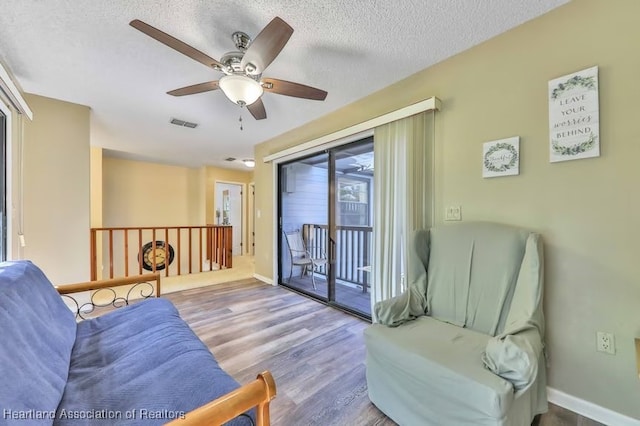 sitting room featuring ceiling fan, a textured ceiling, and light wood-type flooring