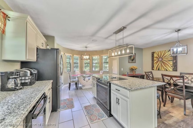 kitchen with hanging light fixtures, light tile patterned floors, light stone countertops, appliances with stainless steel finishes, and a kitchen island