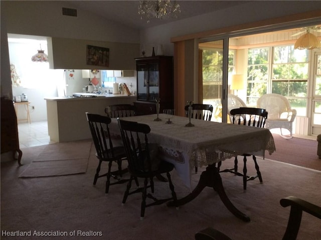 dining area with lofted ceiling, light carpet, and a chandelier