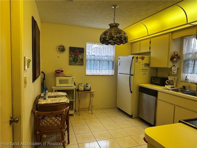 kitchen featuring pendant lighting, light tile patterned flooring, sink, white appliances, and a textured ceiling