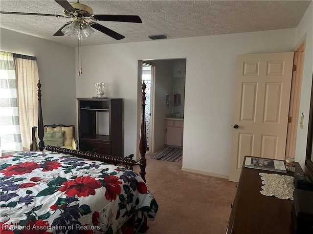 bedroom featuring light carpet, ceiling fan, ensuite bathroom, and a textured ceiling