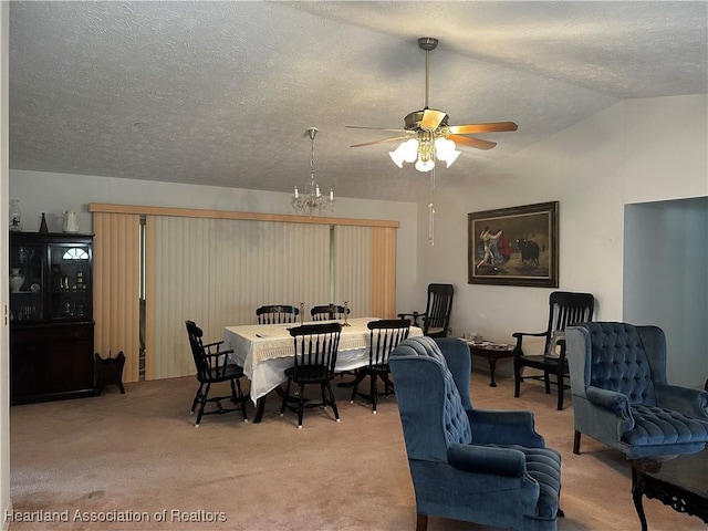 carpeted dining area with ceiling fan with notable chandelier, a textured ceiling, and vaulted ceiling