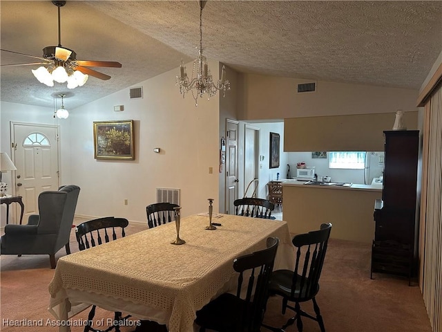 carpeted dining space featuring a textured ceiling, vaulted ceiling, and ceiling fan with notable chandelier