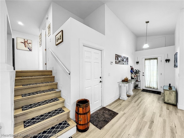 foyer entrance featuring high vaulted ceiling and light hardwood / wood-style floors