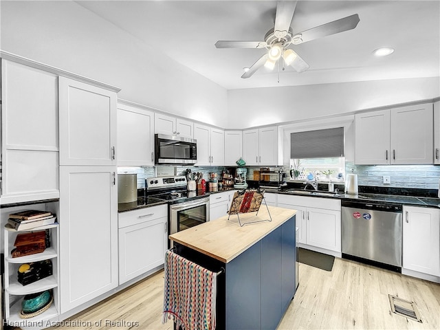 kitchen with white cabinets, sink, vaulted ceiling, tasteful backsplash, and stainless steel appliances