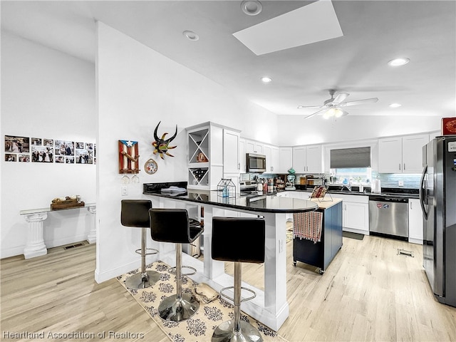 kitchen with a kitchen bar, appliances with stainless steel finishes, kitchen peninsula, and white cabinetry