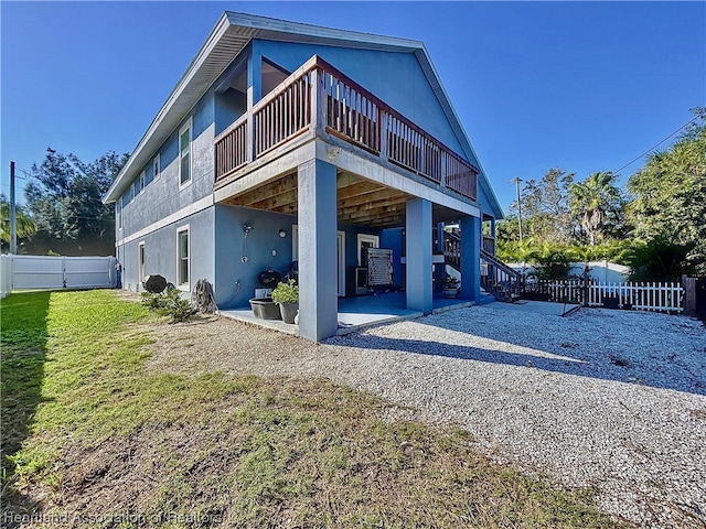 back of property with a yard, a patio area, and a balcony