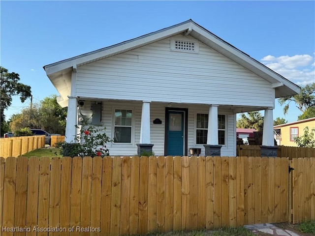 bungalow-style house with a porch and a fenced front yard