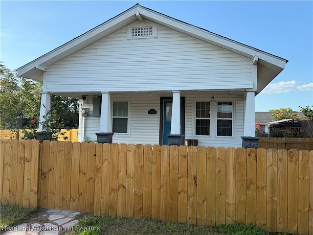 bungalow with a porch and a fenced front yard