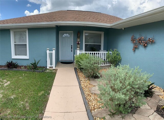 2010 W Royalton Rd, Avon Park, FL 33825 - property entrance with stucco siding, covered porch, and a shingled roof