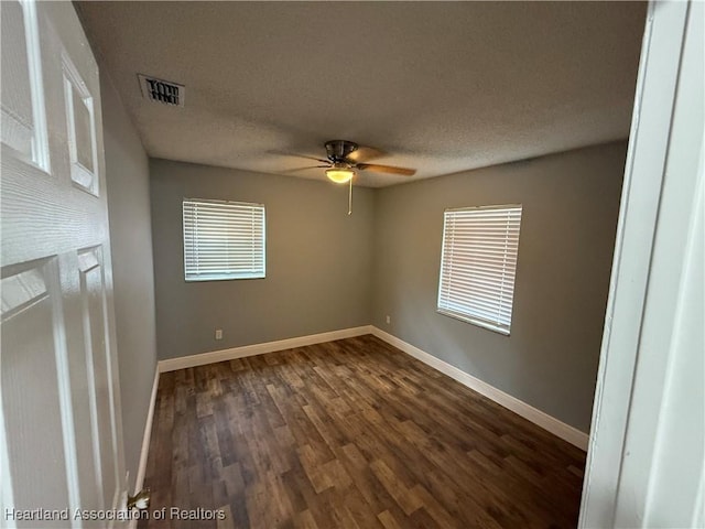 empty room with ceiling fan, dark wood-type flooring, and a textured ceiling