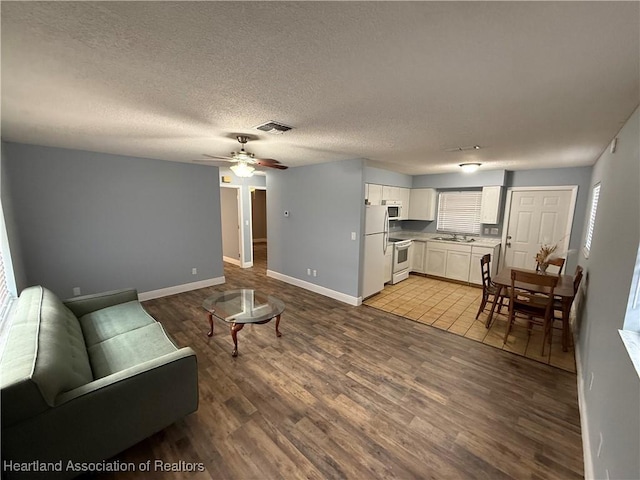 living room with ceiling fan, sink, a textured ceiling, and light hardwood / wood-style flooring