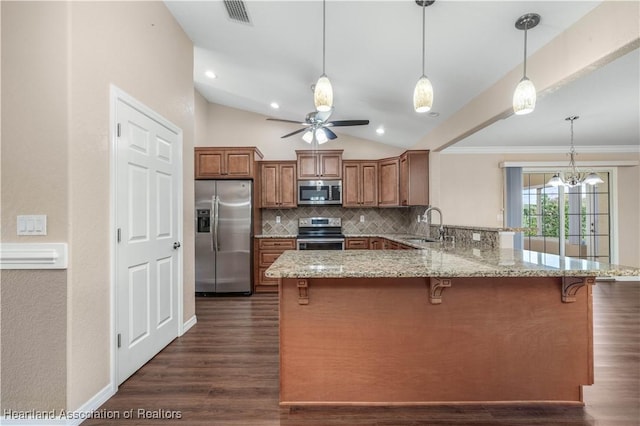 kitchen with appliances with stainless steel finishes, pendant lighting, sink, backsplash, and kitchen peninsula