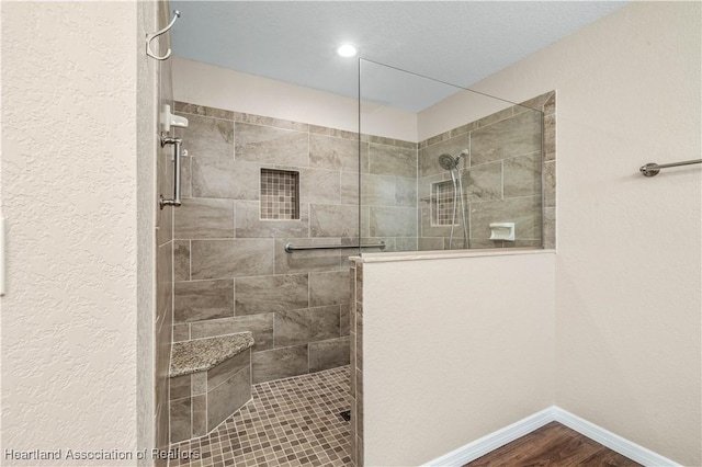 bathroom featuring hardwood / wood-style floors and a tile shower