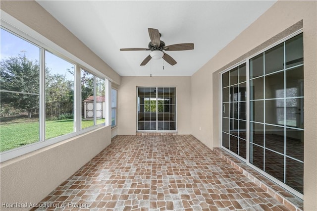 unfurnished sunroom with ceiling fan