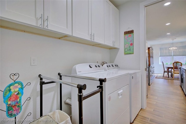 laundry room with cabinets, a notable chandelier, independent washer and dryer, and light wood-type flooring