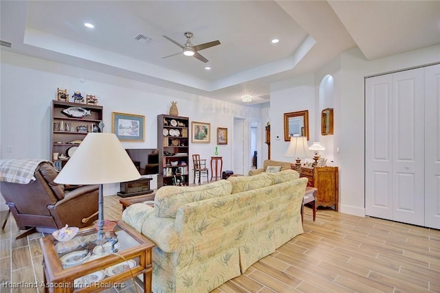 living room with a raised ceiling and ceiling fan