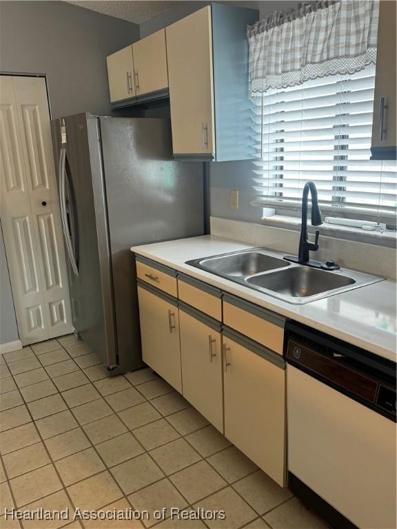 kitchen featuring light tile patterned floors, white dishwasher, stainless steel refrigerator, and sink