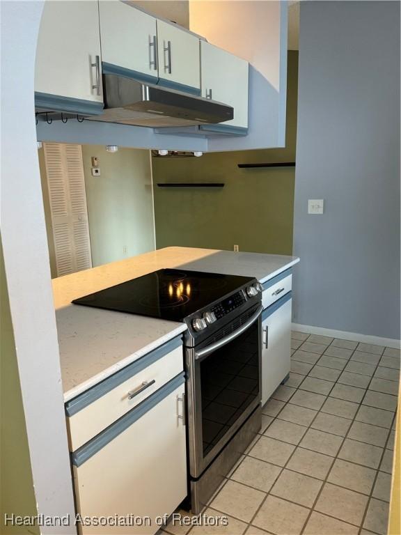 kitchen with white cabinets, electric range oven, and light tile patterned flooring