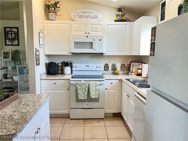 kitchen with lofted ceiling, white cabinetry, white appliances, and light tile patterned floors