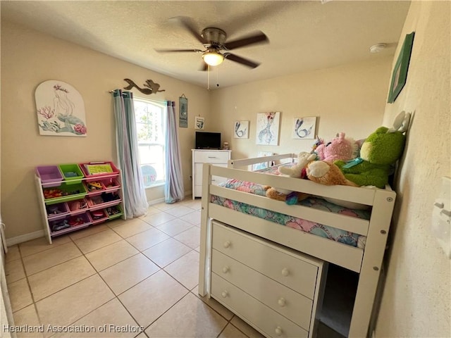 tiled bedroom with ceiling fan and a textured ceiling