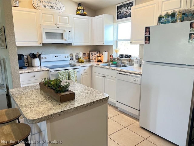 kitchen featuring sink, light tile patterned floors, white appliances, a breakfast bar area, and white cabinets