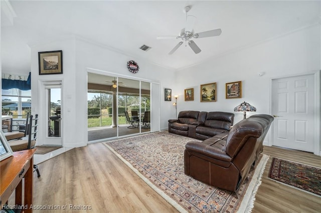 living room with light hardwood / wood-style floors, ceiling fan, and ornamental molding