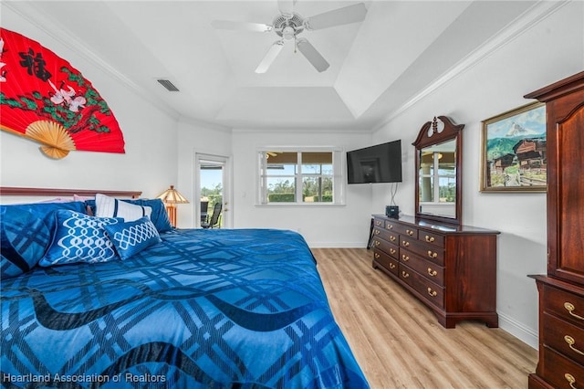 bedroom featuring light wood-type flooring, a tray ceiling, ceiling fan, and ornamental molding