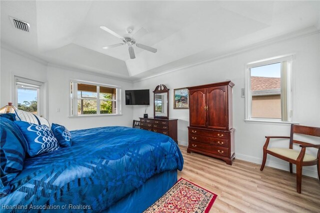 bedroom with a tray ceiling, light hardwood / wood-style flooring, ceiling fan, and crown molding