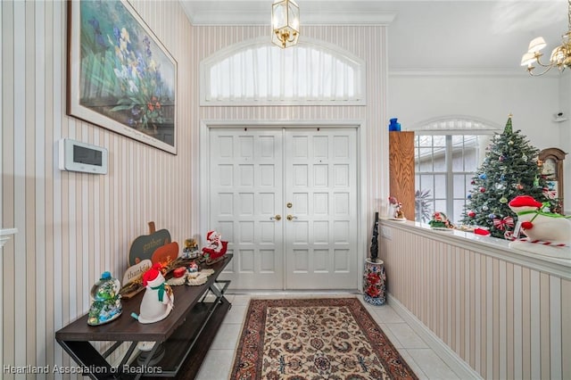 tiled entrance foyer featuring plenty of natural light, ornamental molding, and an inviting chandelier