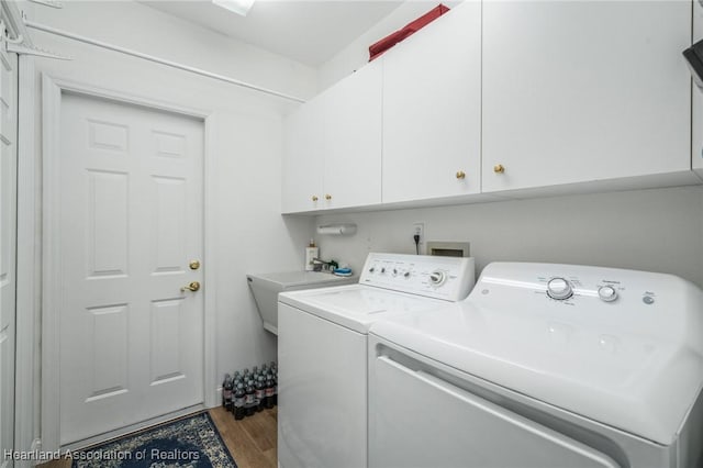 clothes washing area with cabinets, hardwood / wood-style floors, washer and dryer, and sink