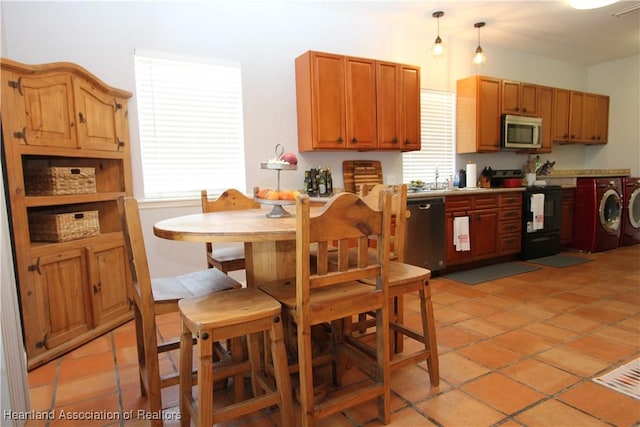 kitchen with washer and dryer, light tile patterned flooring, black appliances, and decorative light fixtures