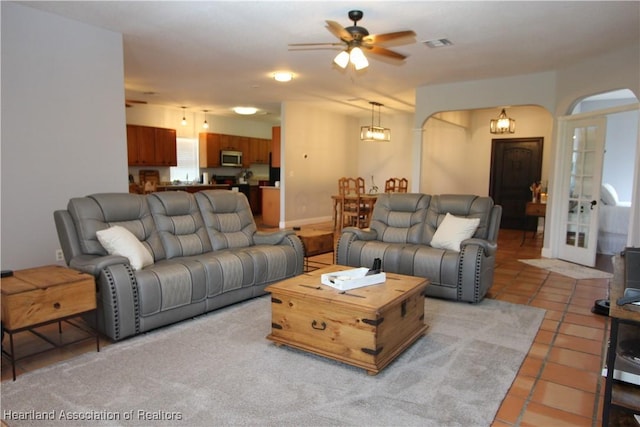 tiled living room featuring ceiling fan and french doors