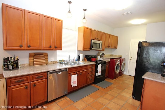 kitchen featuring sink, washing machine and dryer, decorative light fixtures, light tile patterned floors, and black appliances