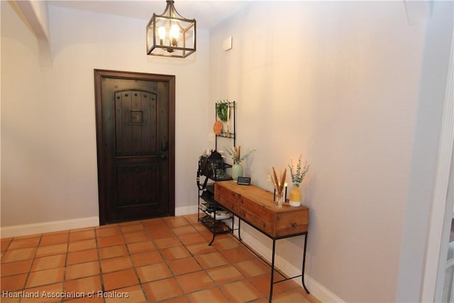 tiled entrance foyer featuring a notable chandelier