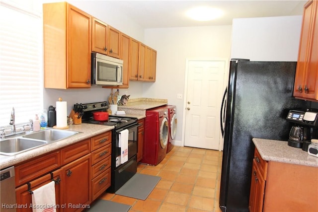 kitchen with light tile patterned floors, sink, washing machine and dryer, and black appliances